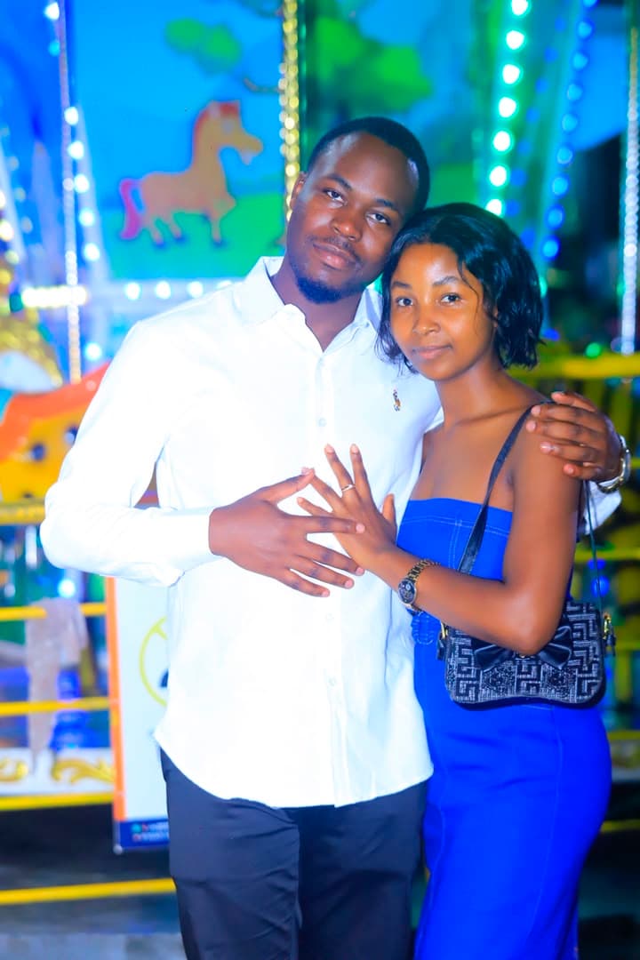 Hanniel et Jessica enlacés devant un manège illuminé, la bague de fiançailles au doigt